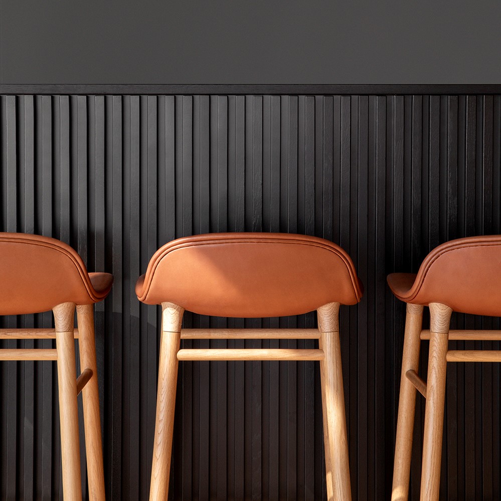 Details of bar stools with brown leather seats and wooden legs