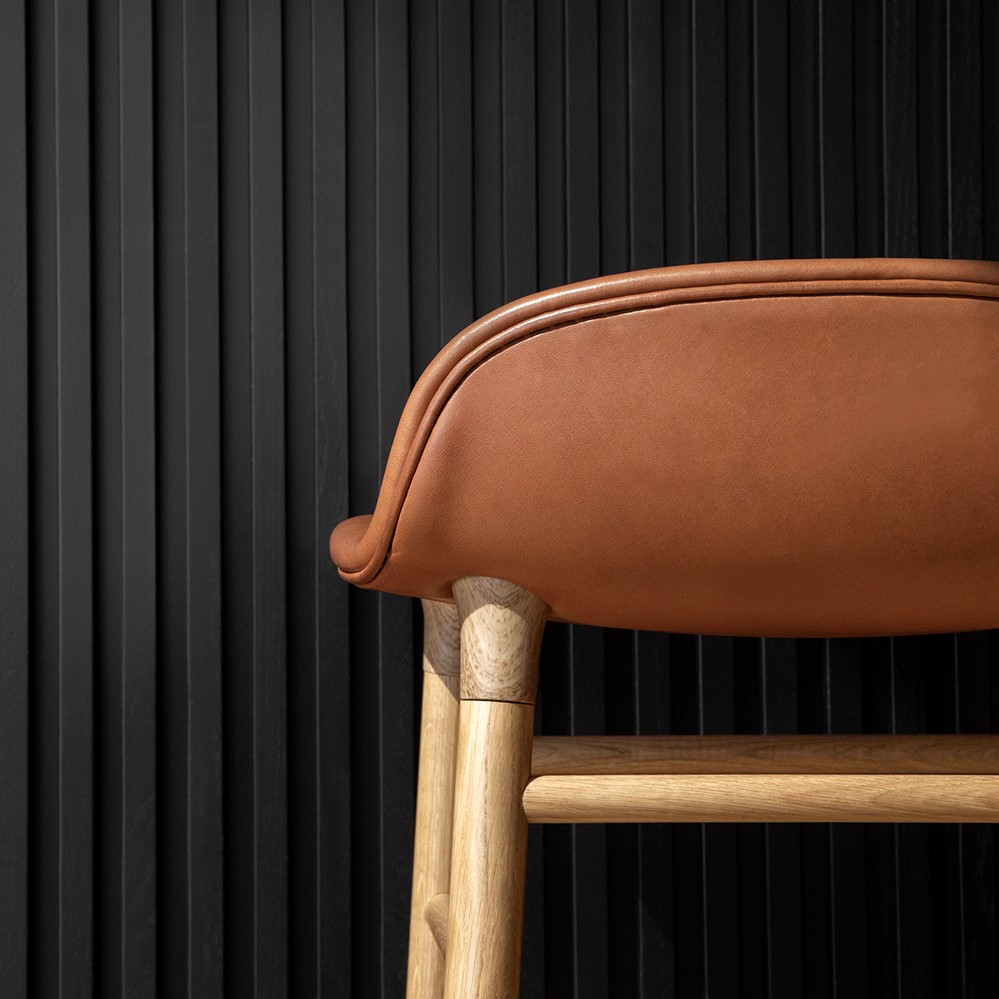 Details of a bar stool with a brown leather seat and wooden legs