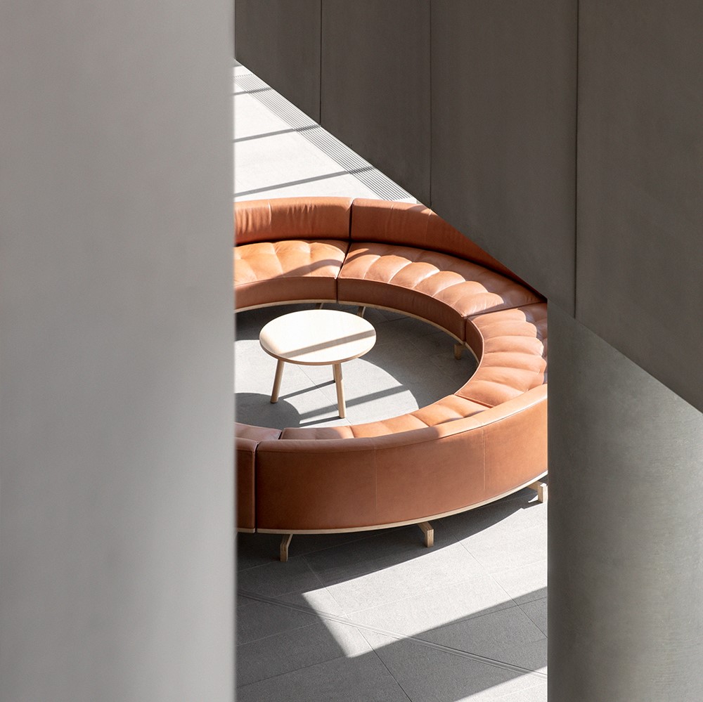 Round, brown leather sofa inside concrete building