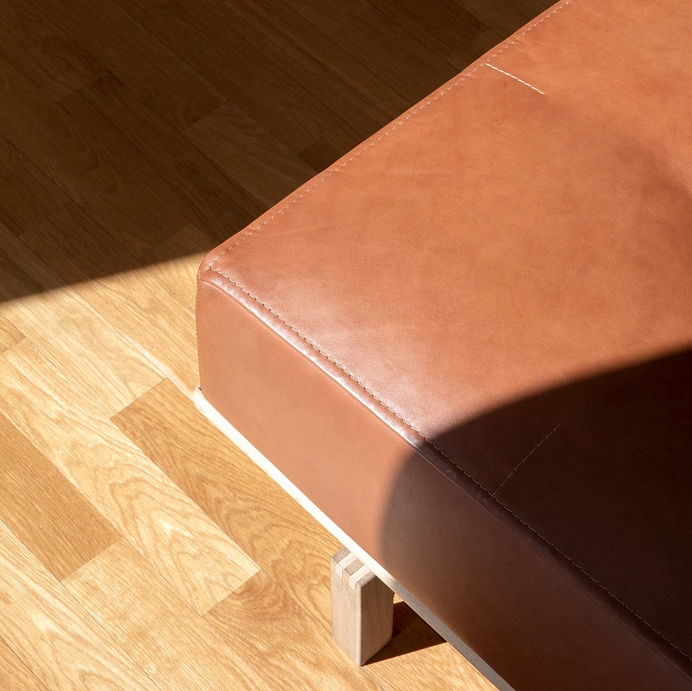 Corner of brown leather sofa with wooden frame