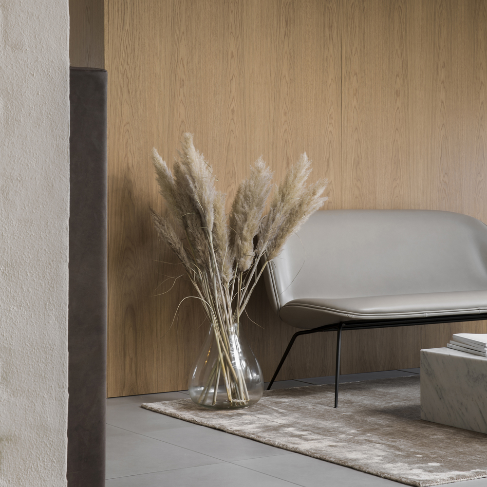 Inside Sørensen Leather HQ decorated with a light grey leather sofa in front of a wooden wall